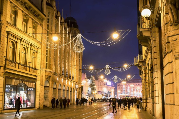 Street with festive lights and people in city at night.