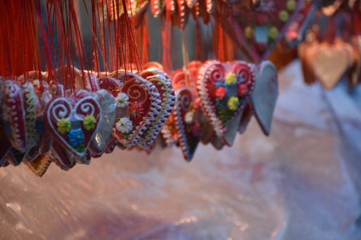 Colorful heart-shaped cookies hanging on red strings at a market stall.