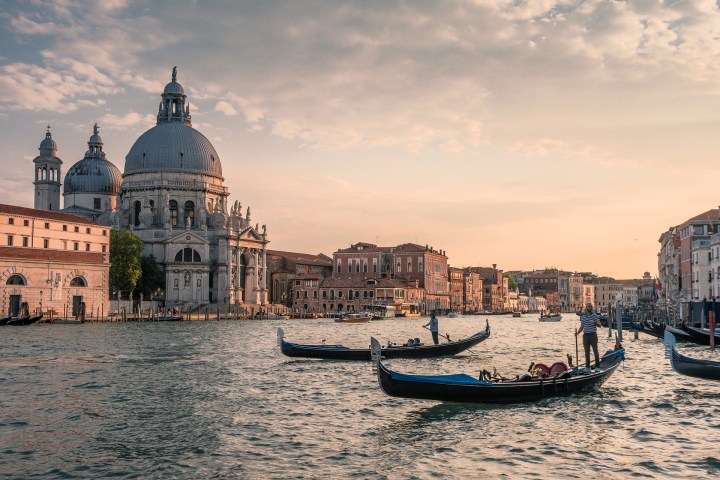 Gondolas on the Grand Canal in Venice at sunset with a view of historic buildings.
