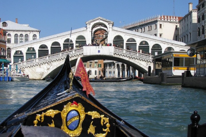 View from a gondola approaching the Rialto Bridge over a canal in Venice.