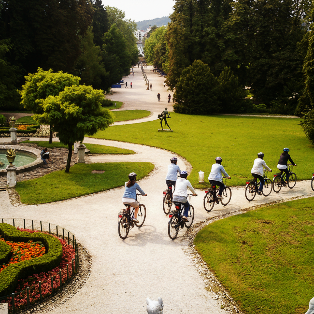Cyclists on a park path surrounded by greenery and a circular fountain.