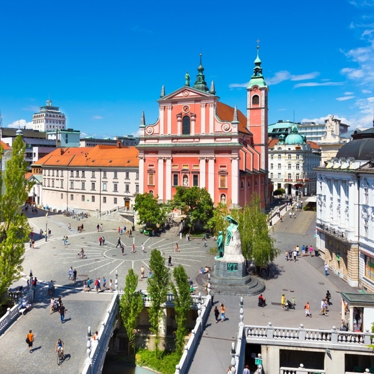 Aerial view of a vibrant city square with a pink church and people walking.