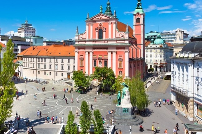 Aerial view of a vibrant city square with a pink church and people walking.