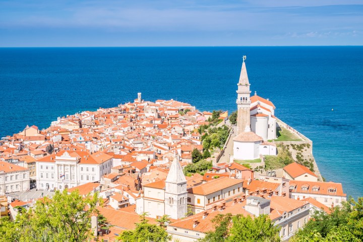 Aerial view of a coastal town with red-roofed buildings and a prominent church by the sea.