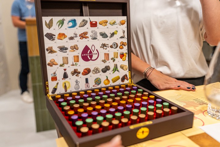 Box with colorful vials and aroma chart, person in white shirt nearby.